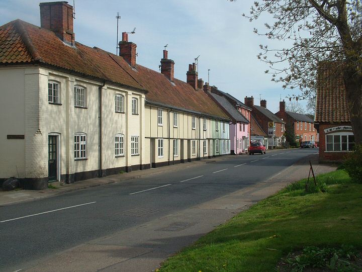 Bramfield is enriched by its wonderful mix of house sizes and styles, old and new, with attractive roofscapes which add interest and are easy on the eye. This is the route of the A144, which also serves as the main road through the village. Just along from this spot is an iron milepost/mileiron dated 1818 recording Bramfield is 98 miles from London, showing that this is a very old, much travelled road. 